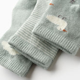 Close-up of Minty Duck baby socks with detailed embroidered patterns in sage tones